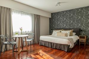 a bedroom with a bed and a table with chairs at Argenta Tower Hotel & Suites in Buenos Aires
