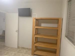 una estantería de madera en una habitación con puerta en Lindo Apartamento Pé na Areia Canto do Forte en Solemar