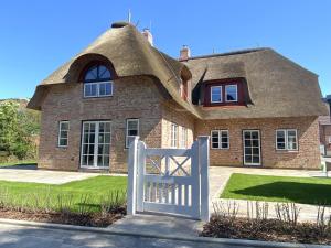a house with a thatched roof and a white gate at Lokelk Lunhüs Hausteil 3 in Oevenum