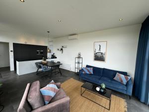 a living room with a blue couch and a table at Enkhuizer Strand Chalet Strandpanorama Zweite Reihe mit Zaun Hausnr 203 in Enkhuizen