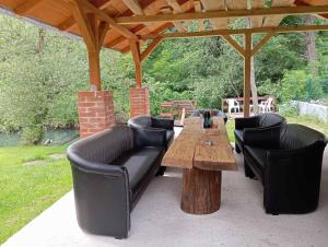 a patio with a wooden table and black leather furniture at Pure Nature in Bihać