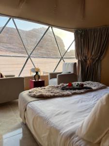a large bed in a room with a large window at Golden Gate Luxury Camp in Wadi Rum
