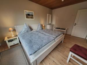 a bedroom with a bed with a blue comforter at Haus Ruhewinkel, Bungalow 1 in Alkersum