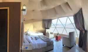 a bedroom with a bed and a chair and a window at Golden Gate Luxury Camp in Wadi Rum