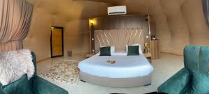 - une chambre avec un grand lit et deux chaises dans l'établissement Golden Gate Luxury Camp, à Wadi Rum