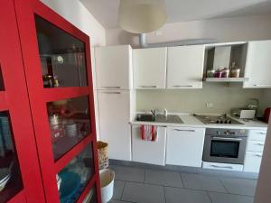 una cucina con armadietti bianchi e una porta rossa di La Ginestra di Lido di Camaiore a Camaiore