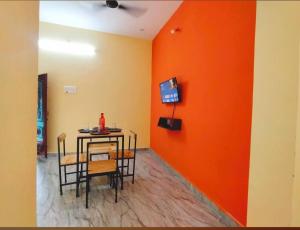 comedor con pared de color naranja, mesa y sillas en Gratitude Retreat en Pondicherry