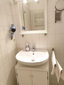 La salle de bains est pourvue d'un lavabo blanc et d'un miroir. dans l'établissement Wiesenweg W07, à Laboe