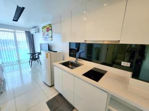 Una cocina blanca con fregadero y refrigerador. en City Center Residence CCR, en Pattaya central