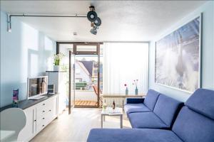 a living room with a blue couch and a large window at Fewo Mann in Laboe