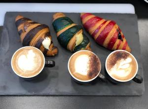 four cups of coffee on a tray with pastries at Ippocampo alba e tramonto al giardino in Ippocampo