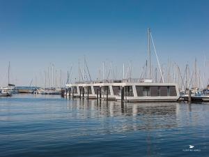 a boat is docked at a dock in the water at Hausboot Floating Homes - A-Type Laboe FH-LA-03 Baltic Bay in Laboe