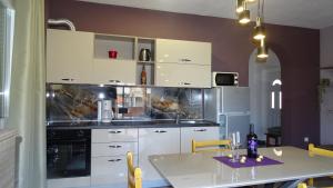 a kitchen with white cabinets and a white table with a table at Apartments Luna in Sukošan
