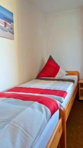 ein Bett mit einem roten Kissen darüber in der Unterkunft Leuchtfeuer in Wendtorf