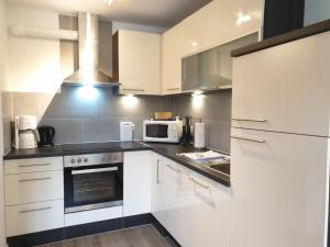 a kitchen with white cabinets and a microwave at Wiesenweg W09 in Laboe