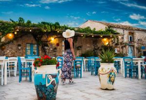 a woman in a hat standing in front of a restaurant at La dimora di nonna Giuseppa in Pachino