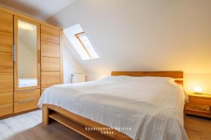 a bedroom with a large white bed and a skylight at Kapitänshaus Fewo Seemann Budle in Laboe