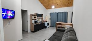 a living room with a couch and a tv and a kitchen at Apartamento modelo chalé 202 in Santo Ângelo
