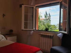 a bedroom window with a view of a church at Hotel Alvaro frente Palacio-Museo Selgas in Cudillero