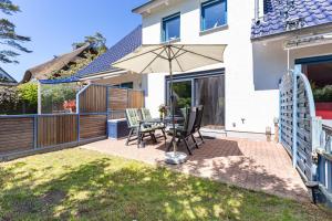 a patio with a table and chairs and an umbrella at Ostseeromantik in Neuhaus