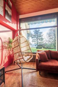 eine Rattanschaukel in einem Zimmer mit Sofa und Fenster in der Unterkunft Villa avec vue panoramique in Charleville-Mézières