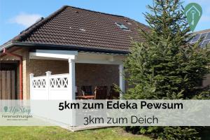 a house with a white gate and a fence at Ferienwohnung Behle in Krummhörn