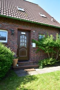 a brick house with a brown door and a yard at Haus Piratenperle - Hooksiel in Wangerland