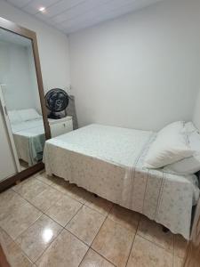Schlafzimmer mit einem weißen Bett und einem Spiegel in der Unterkunft Casa aconchegante ao lado da Igreja Matriz- Bananeiras-PB in Bananeiras
