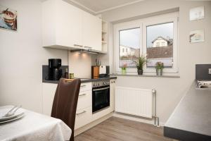 uma cozinha com armários brancos e um forno com placa de fogão em Ferienhaus Störtebeker em Laboe