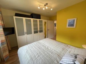 ein Schlafzimmer mit einem Bett und einer gelben Wand in der Unterkunft Blauer Blick 12 in Laboe