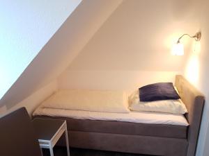 Cama en habitación pequeña con lámpara en Wiesenweg W17 en Laboe