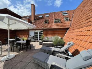 un patio con mesas, sillas y una sombrilla en Wiesenweg W17 en Laboe