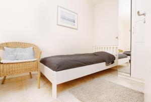 1 dormitorio blanco con 1 cama y 1 silla en Erholungszentrum FeWo 25, en Laboe