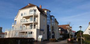 a tall white building with balconies on a street at Fewo Panorama 14 in Laboe