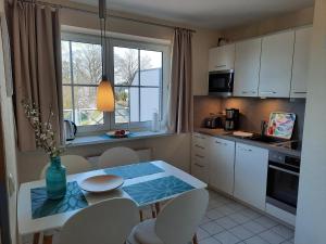 a kitchen with a table and chairs and a window at Nautic W22 in Laboe