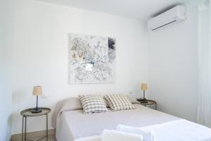 a white bedroom with a bed and two lamps at Cas Buc - Villa con piscina a pasitos del mar in Cala Blanca