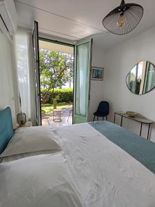 sypialnia z białym łóżkiem i przesuwnymi szklanymi drzwiami w obiekcie Garden Atlantide Promenade w Nicei