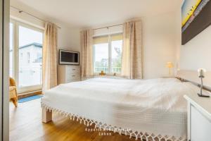 - une chambre blanche avec un grand lit et des fenêtres dans l'établissement Villa Fördestrand W06, à Laboe
