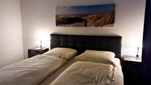 拉博埃Fewo Sanddüne nur wenige Minuten vom Hafen und Strand entfernt的一间卧室设有两张床和两张台灯。