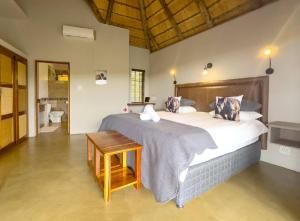 ein Schlafzimmer mit einem großen Bett und einem Tisch in der Unterkunft Kanaan, Mabalingwe in Mabula