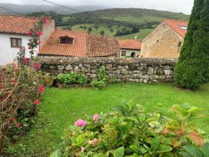 a yard with a stone wall and a house at La Casina de Lucia in Merodio