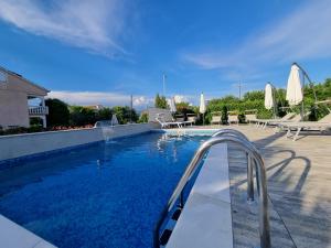 a swimming pool with chairs and umbrellas at Apartments Lea with pool in Malinska