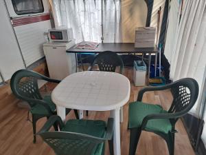 Biały stół z 4 krzesłami i biurko w pokoju w obiekcie Camping Valle del Andarax w mieście Fondón