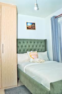a small bedroom with a bed with a green headboard at Magazi suites 3 in Nairobi