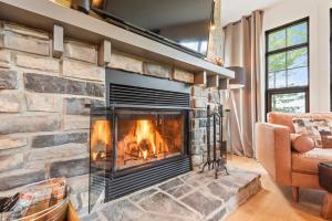 a fireplace in a living room with a stone wall at Tremblant Prestige - Les Eaux 235-1 in Mont-Tremblant