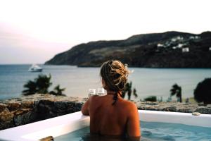a woman sitting in a bath tub looking out at the water at Sea Side Studios & Houses in Kalo Livadi