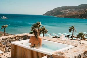 a woman sitting in a bath tub looking at the ocean at Sea Side Studios & Houses in Kalo Livadi