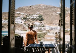 a woman in a bikini sitting on a balcony looking out at a mountain at Sea Side Studios & Houses in Kalo Livadi