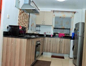 cocina con armarios de madera y nevera en Magazi suites 3, en Nairobi