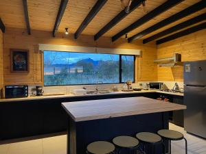 a kitchen with a large window and a counter with stools at Cabaña Negra in Riñinahue